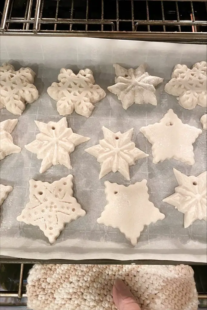 cookie sheet with parchment paper and salt dough ornaments going in the oven.